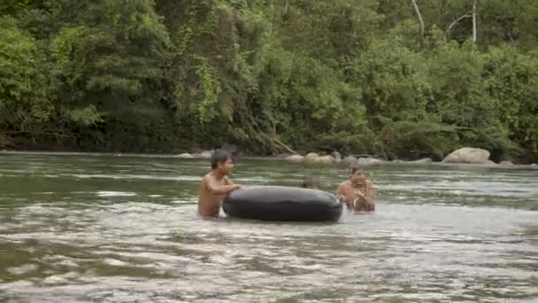 Niños indígenas juegan en un agua con un neumático flotante — Vídeos de Stock