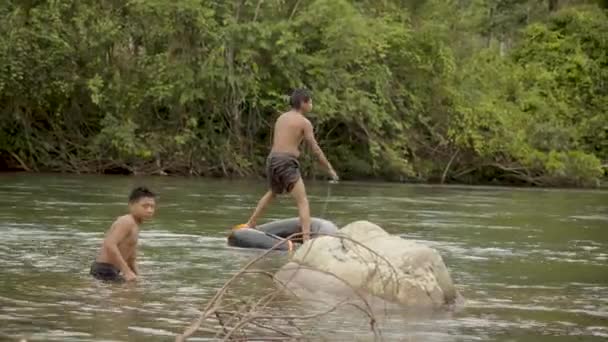 Dos chicos indígenas juegan en un agua con un neumático flotante — Vídeos de Stock