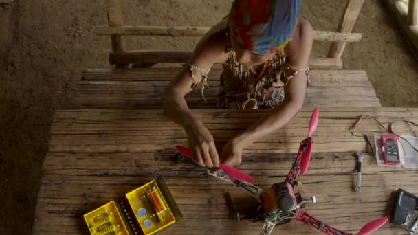 Giovane uomo indigeno sta costruendo un drone nella sua capanna rurale — Video Stock