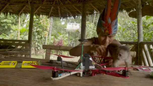 L'uomo indigeno sta costruendo un drone mentre viene distratto da una scimmia — Video Stock