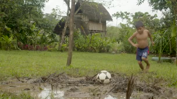 Kleiner indigener Junge kickt einen Ball auf einem ländlichen Fußballplatz — Stockvideo