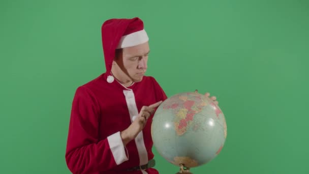 Uomo adulto Babbo Natale trovare posti su un globo — Video Stock