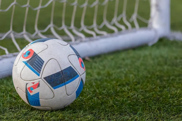 A football lying separately in the goal line on the grass.