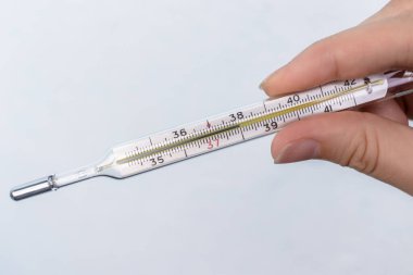 İnsan eli sıhhiye termometresini tutuyor. Cıva termometre ölçeğinde 38 derece yüksek sıcaklık.