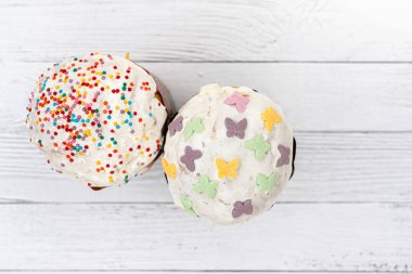 Beyaz panoların arka planında beyaz kremalı iki Paskalya pastası. Bahar tatili için geleneksel dekore edilmiş turtalar.