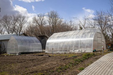 Sebze ve meyve yetiştirmek için iki sera. Polikarbonat prefabrik sera. Bahçede plastik yapı.