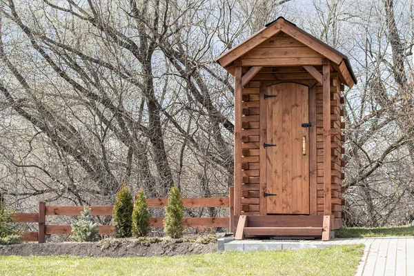早春の木の背景に木製の素朴なトイレ 近代的な田舎の木造トイレ 田舎の木造生態堆肥トイレ ストック写真