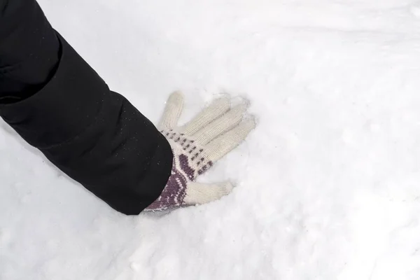 A mão de uma menina em uma luva empurra através da neve — Fotografia de Stock