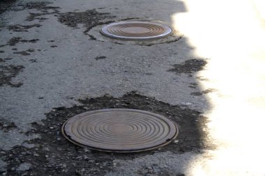 Kaldırımda iki rögar kapağı.