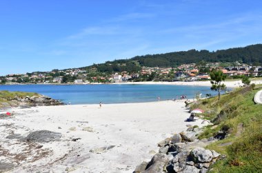Kumsalda insanlar, mavi suyla körfez. Areas Beach, Rias Baixas, Pontevedra Eyaleti. Sanxenxo, İspanya. 12 Mayıs 2019.