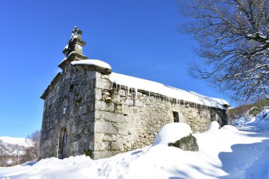 Buz saçakları ve mavi gökyüzü olan kar yağışı sonrası Ermita de San Lorenzo dağ kilisesi. Piornedo Köyü, Ancare, Lugo, Galiçya, İspanya.