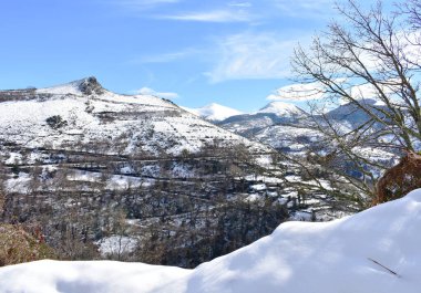Karlı dağlarla, ağaçlarla ve mavi gökyüzüyle kış manzarası. Ancare, Lugo, Galiçya, İspanya.