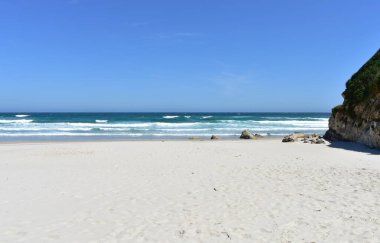 Uçurumlu, kayalıklı ve dalgalı beyaz kumlu yaz manzarası. Viveiro, Lugo, Galiçya, İspanya.