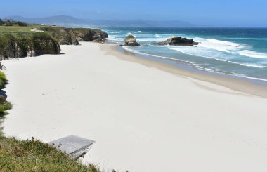 Uçurumlu, kayalıklı ve dalgalı beyaz kumlu yaz manzarası. Viveiro, Lugo, Galiçya, İspanya.