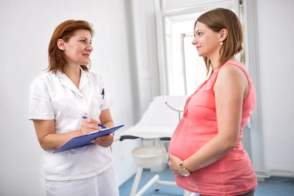 Nurse weighing pregnant woman in office — Stock Photo, Image
