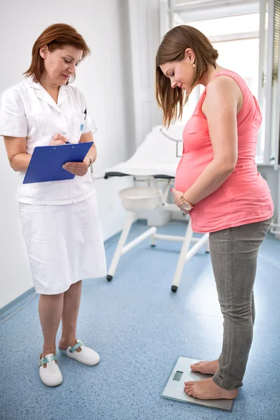 Enfermeira pesando mulher grávida no escritório — Fotografia de Stock