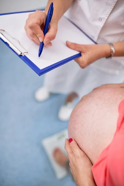 Enfermera que pesa a una mujer embarazada en la oficina — Foto de Stock