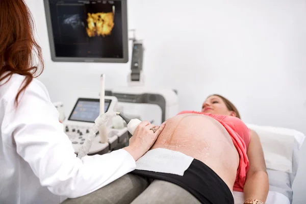 Pregnant woman getting ultrasound from doctor — Stock Photo, Image