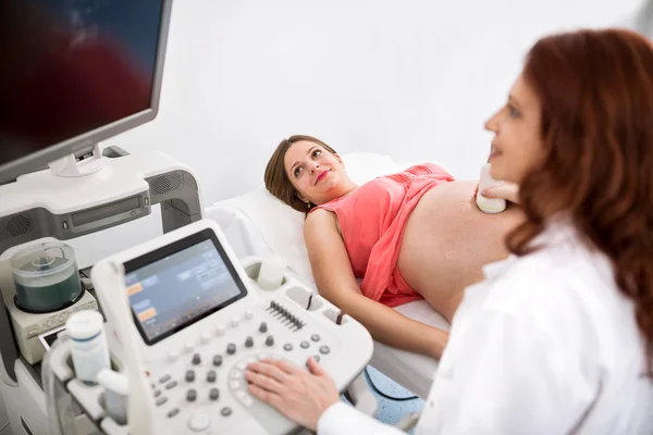 Pregnant woman looking at ultrasound results with doctor — Stock Photo, Image