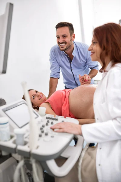 Casal feliz olhando para os resultados de ultra-som com médico — Fotografia de Stock