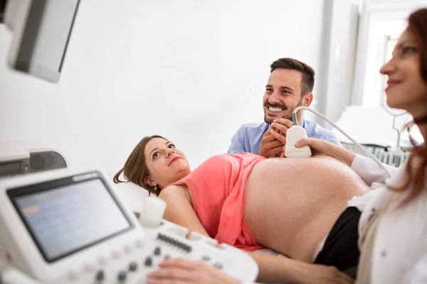 Young happy smiling couple looking at results of ultrasound mach — Stock Photo, Image
