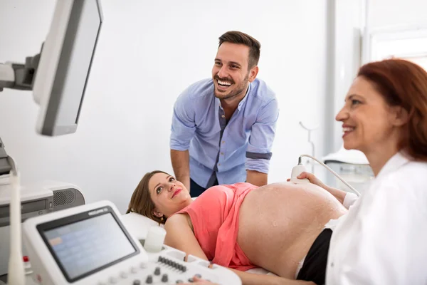 Casal feliz olhando para os resultados de ultra-som com médico — Fotografia de Stock