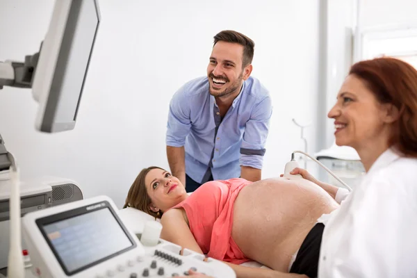 Gelukkige paar looking at echografie resultaten met arts — Stockfoto