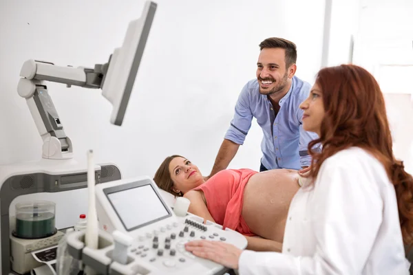 Feliz e jovem casal olhando para os resultados de ultra-som com o médico — Fotografia de Stock