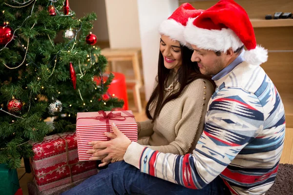 Jeune couple en chapeaux de Noël tenant des cadeaux — Photo