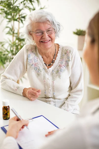 Лікар пише рецепт для пацієнта старшої жінки — стокове фото
