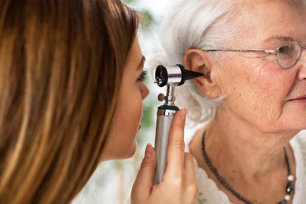 Dokter memegang otoskop dan memeriksa telinga wanita senior — Stok Foto