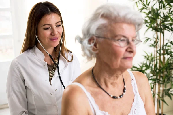 Young doctor with stethoscope exam senior woman — Stock Photo, Image