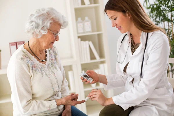 Young female doctor making diabetes blood test on senior woman — Stock Photo, Image