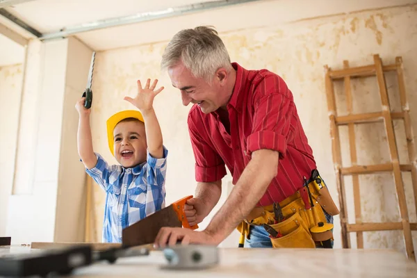 Sonriente niño está ayudando a su abuelo en el taller —  Fotos de Stock