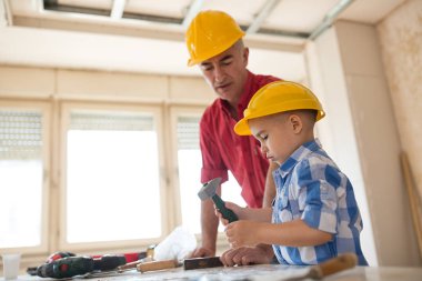 Dede ve torunu bir sazan çekiçle çivi çalıyor