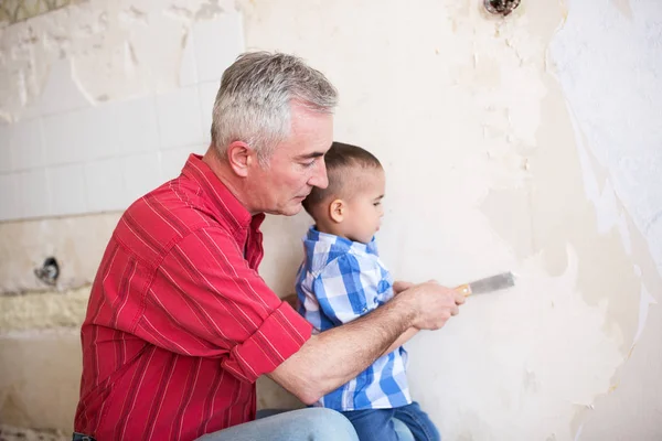 Nieto está ayudando a su abuelo en la eliminación de papel pintado — Foto de Stock