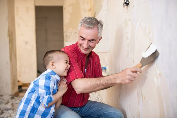 Grand-père enlève le papier peint et rit avec son petit-fils — Photo