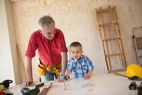 El nieto está ayudando al abuelo en un taller de carpintería. — Foto de Stock