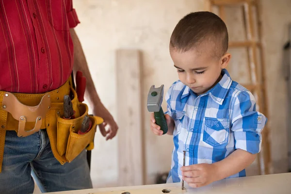 Hermoso chico golpea un clavo con un martillo — Foto de Stock