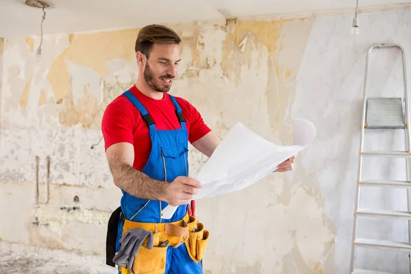 Handyman watchig blueprnts di ristrutturazioni casa — Foto Stock