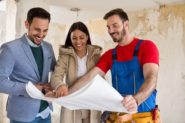 Beutiful jeune couple à la recherche des plans de leur maison avec la main — Photo