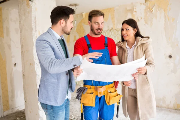 Handyman mostra ai giovani dettagli coppia cianografie della loro casa — Foto Stock