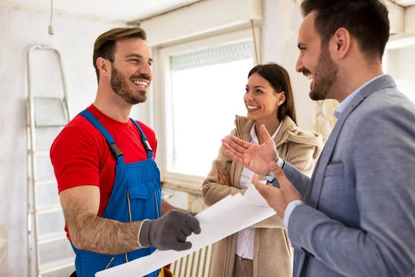 Joven sonriente pareja y constructor manitas hablando de detalles — Foto de Stock