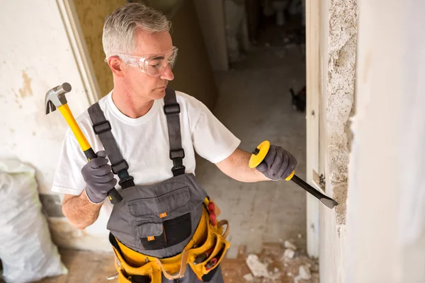 Homme âgé travaillant avec le marteau et l'outil tout en démolir le mur — Photo