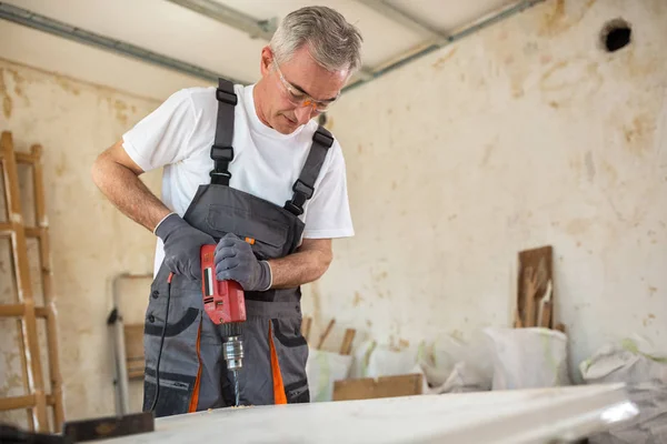 Carpintero utiliza taladros en reparación de puertas viejas — Foto de Stock