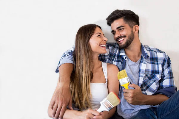 Feliz jovem casal relaxante após a pintura — Fotografia de Stock