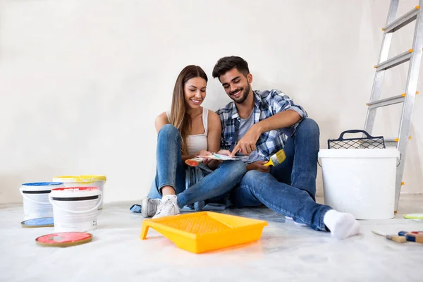 Joven pareja feliz eligiendo colores para pintar su hogar — Foto de Stock