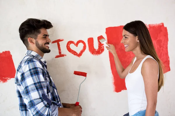 Прекрасна усміхнена щаслива пара малює новий будинок — стокове фото