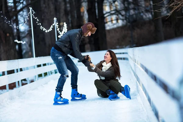 スケート リンクまで上昇する女性を助ける男 — ストック写真
