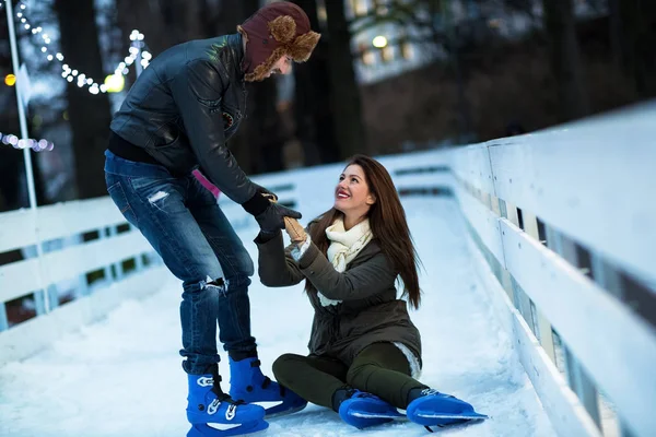 Homme aidant femme à se lever sur patinoire — Photo